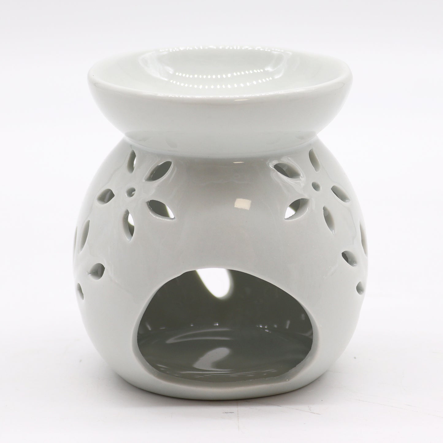 Carefully sourced by The Original Candle Company, this classic white oil burner features an elegant tree cut-out design, now shown from an angle highlighting the tealight access. A timeless piece for essential oils and wax melts, blending charm with practical functionality.