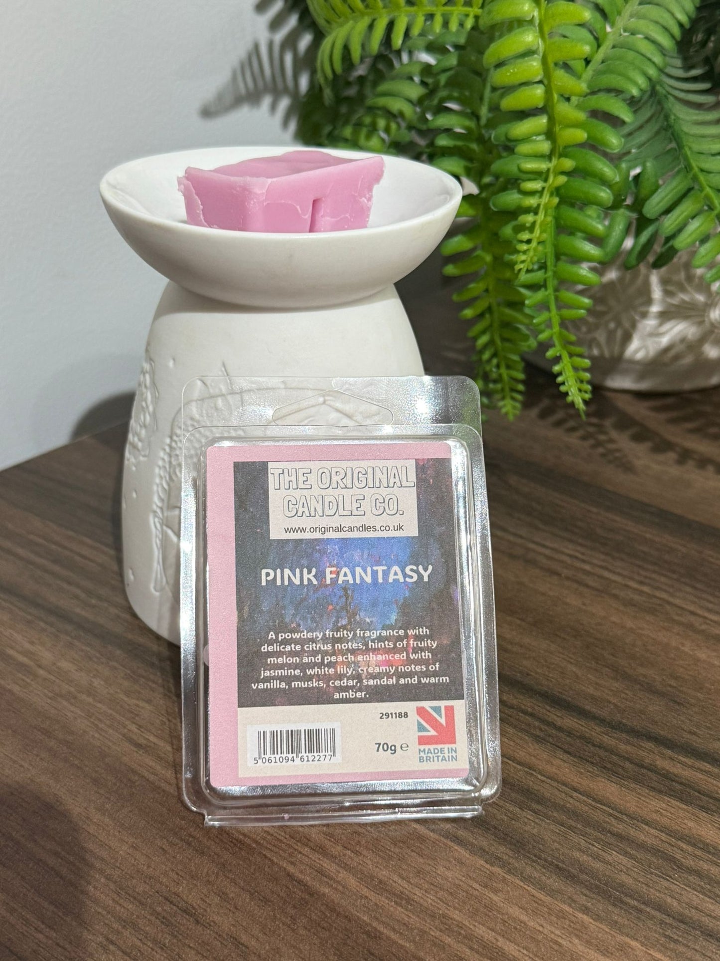 Wax melt container with 'Pink Fantasy' label on a wooden surface with a plant in the background
