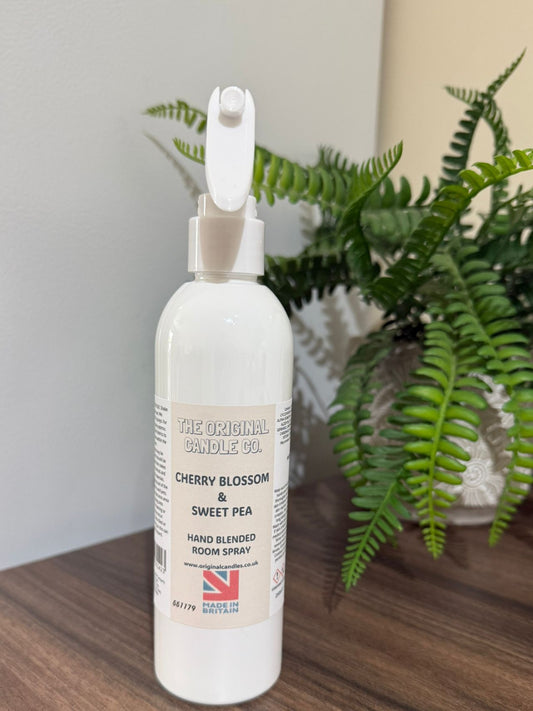 White room spray bottle on a wooden surface with plants in the background