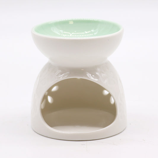 Carefully sourced by The Original Candle Company, this classic white oil burner features a soothing teal well and an intricate floral cut-out design. The image highlights the cut-out section for tealight placement, showcasing its practical functionality alongside its elegant aesthetic.