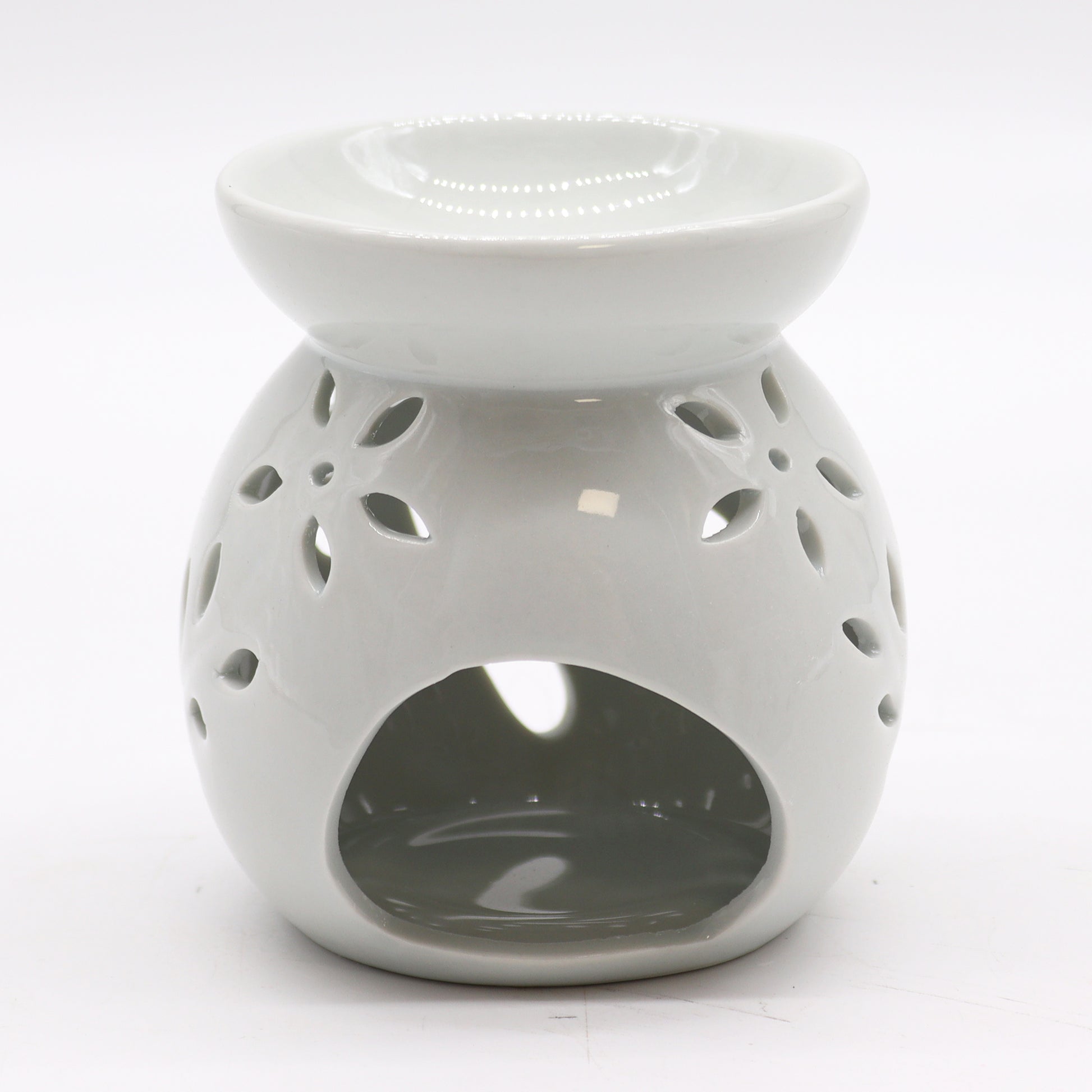 Carefully sourced by The Original Candle Company, this classic white oil burner features an elegant tree cut-out design, now shown from an angle highlighting the tealight access. A timeless piece for essential oils and wax melts, blending charm with practical functionality.