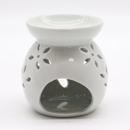 Carefully sourced by The Original Candle Company, this classic white oil burner features an elegant tree cut-out design, now shown from an angle highlighting the tealight access. A timeless piece for essential oils and wax melts, blending charm with practical functionality.
