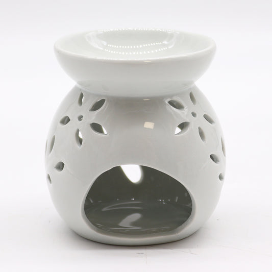 Carefully sourced by The Original Candle Company, this classic white oil burner features an elegant tree cut-out design, now shown from an angle highlighting the tealight access. A timeless piece for essential oils and wax melts, blending charm with practical functionality.