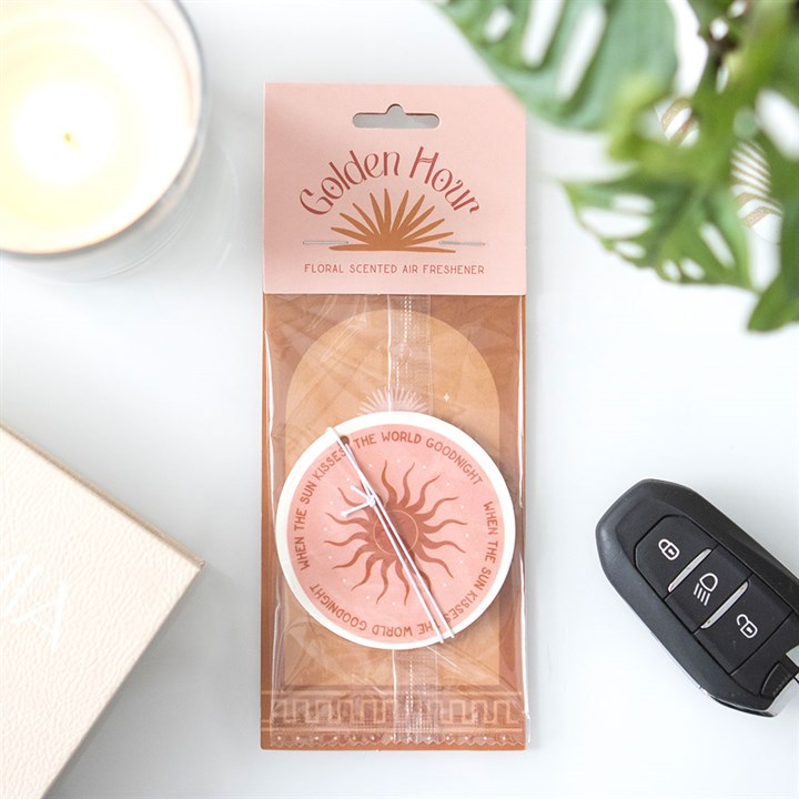 Round car airfreshener with a pink and orange design showing an image of the sun in the outer packaging.