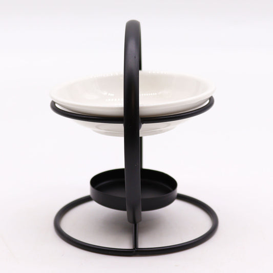 A side perspective of The Original Candle Company’s modern oil burner, featuring a sleek black circular stand and a white removable ceramic warming dish. Designed for essential oils and wax melts, it offers a refined, contemporary touch to home fragrance rituals.