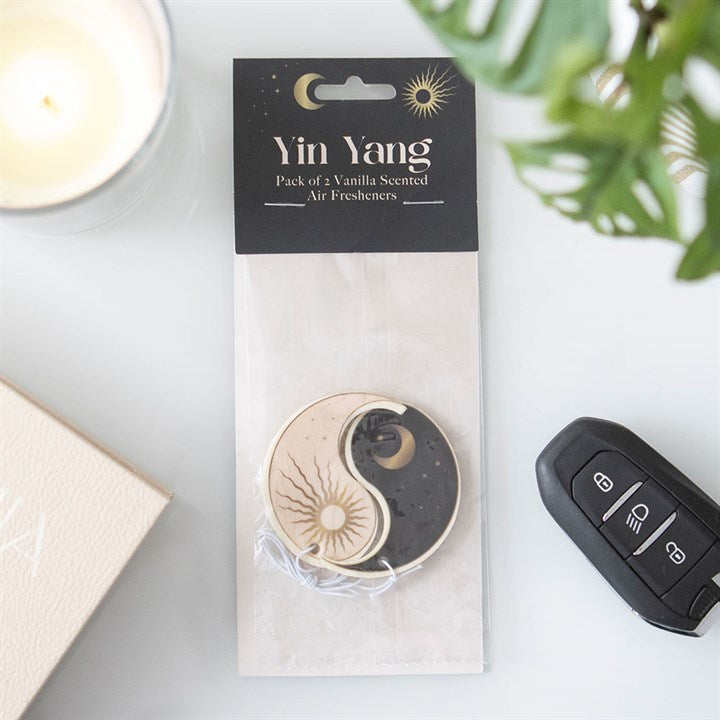 Pack of 2 Yin Yang vanilla scented car airfresheners. One in black with the moon, the other light pink depicting the sun.