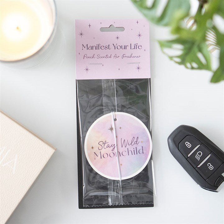 Peach fragranced Manifest Your Life round car air freshener inside the outer packaging.