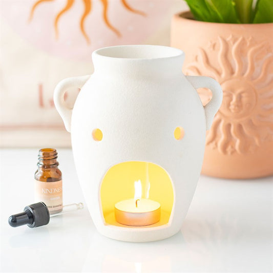 This elegant urn-style oil burner and wax warmer features a beautifully textured finish that will add a touch of sophistication to the home. Perfect for warming your favorite oils or wax melts, this burner will turn any space into a relaxing retreat with its soft, flickering glow as shown in this image from the back of the urn with a lit tealight.